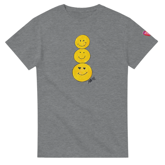A heather gray short-sleeve T-shirt featuring a graphic of three stacked yellow smiley faces on the front, by Ashley Caldwell with a small pink heart patch on the left sleeve.