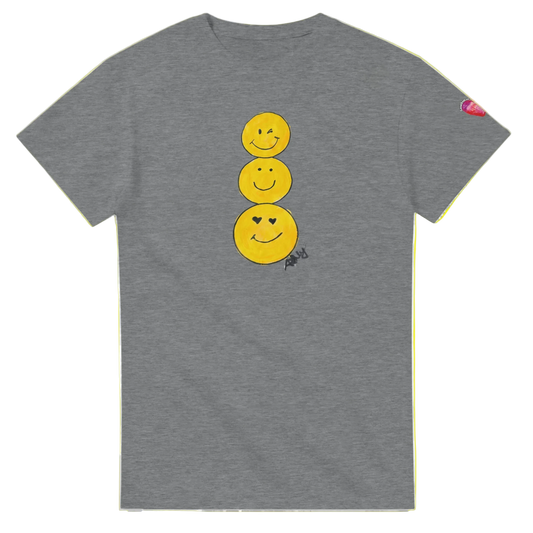 A heather gray short-sleeve T-shirt featuring a graphic of three stacked yellow smiley faces on the front, by Ashley Caldwell with a small pink heart patch on the left sleeve.