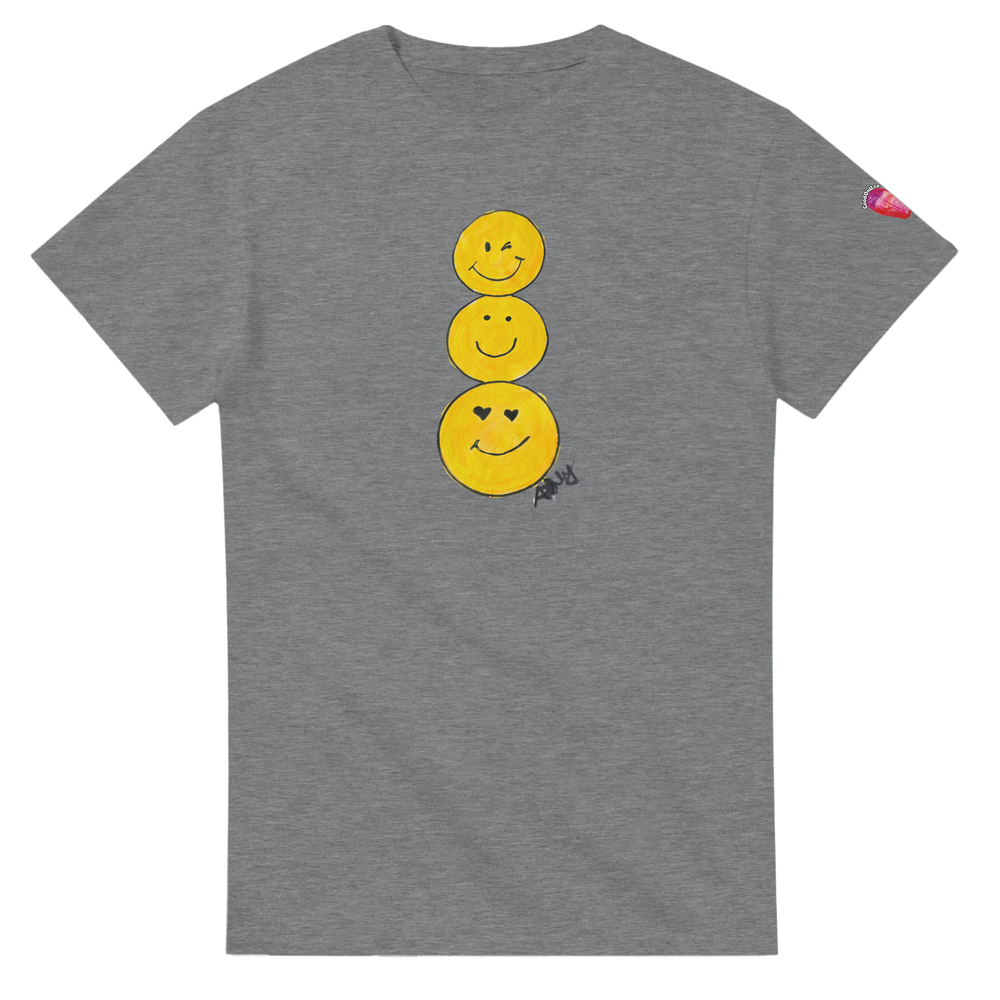A heather gray short-sleeve T-shirt featuring a graphic of three stacked yellow smiley faces on the front, by Ashley Caldwell with a small pink heart patch on the left sleeve.
